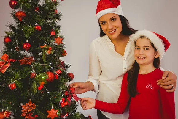 Mother and daughter hanging christmas decorations on tree — Stock Photo, Image