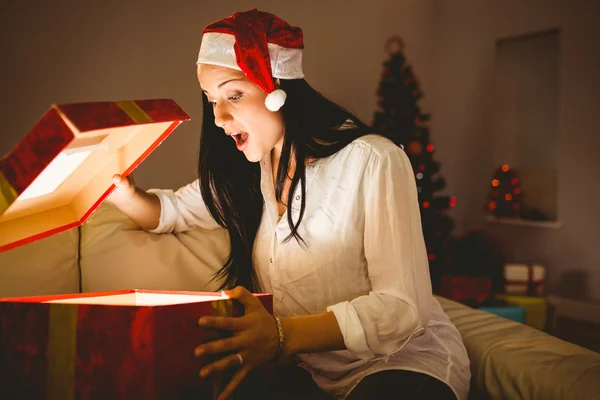 Bruna festiva che apre un regalo di Natale incandescente — Foto Stock