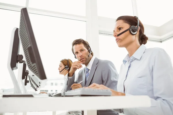 Gente de negocios con auriculares usando computadoras en la oficina —  Fotos de Stock