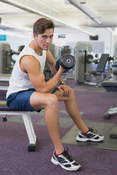 Fit man lifting dumbbells sitting on the bench — Stock Photo, Image
