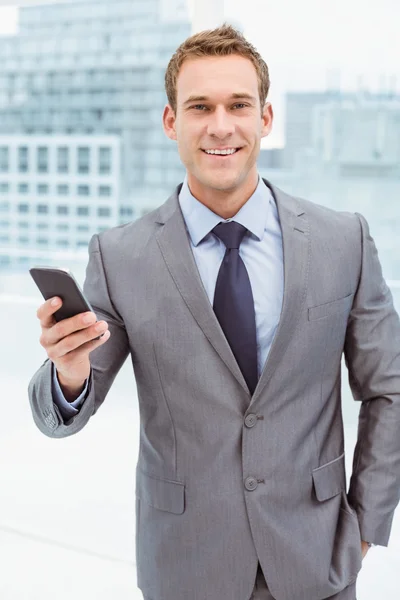 Бізнесмен тримає мобільний телефон в офісі — стокове фото