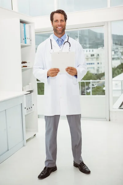 Male doctor holding reports in medical office — Stock Photo, Image