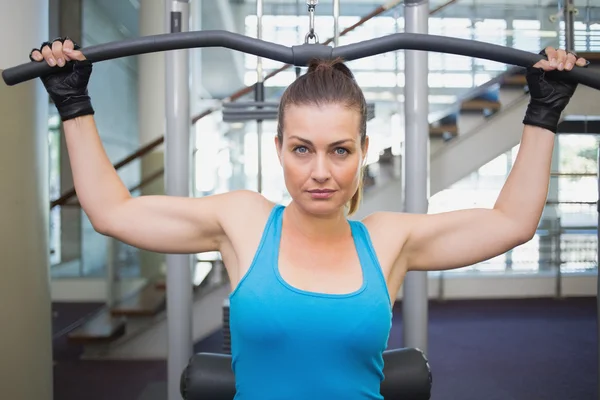 Fit brunette using weights machine for arms — Stock Photo, Image