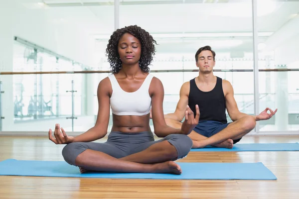 Fit couple sitting in lotus pose in fitness studio — Stock Photo, Image