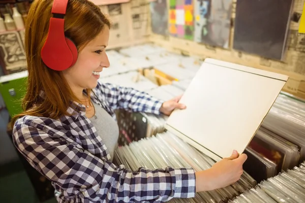 Mujer sonriente escuchando música y sosteniendo vinilos — Foto de Stock