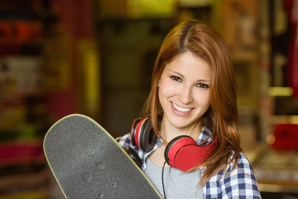 Портрет улыбающейся рыжей женщины, держащей скейтборд — стоковое фото