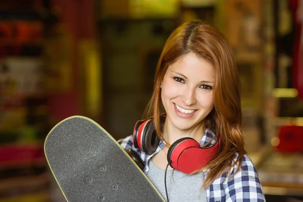 Retrato de uma ruiva sorridente segurando seu skate — Fotografia de Stock