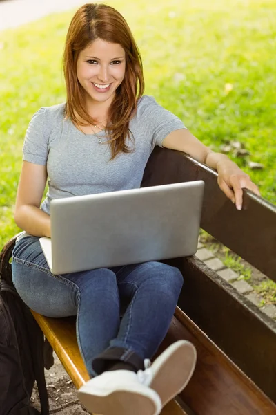 Söt flicka sitter på bänken med laptop — Stockfoto