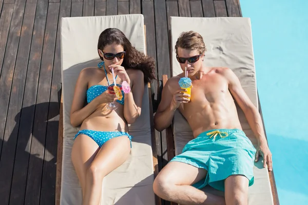 Couple with drinks by swimming pool — Stock Photo, Image