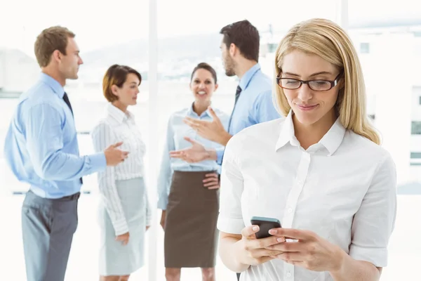 Affärskvinna textmeddelanden med kollegor i möte bakom — Stockfoto