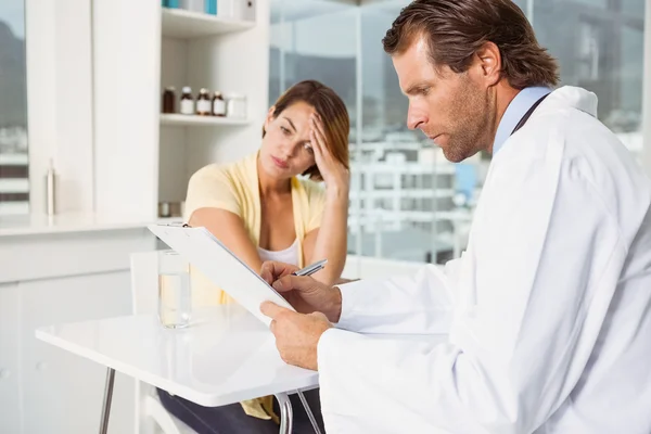 Médico discutindo relatórios com paciente na mesa médica — Fotografia de Stock