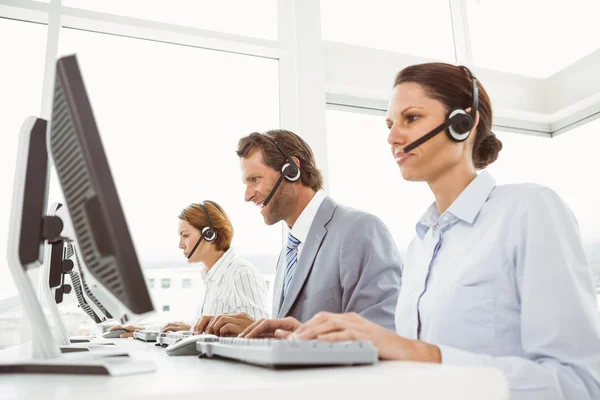 Gente de negocios con auriculares usando computadoras en la oficina —  Fotos de Stock