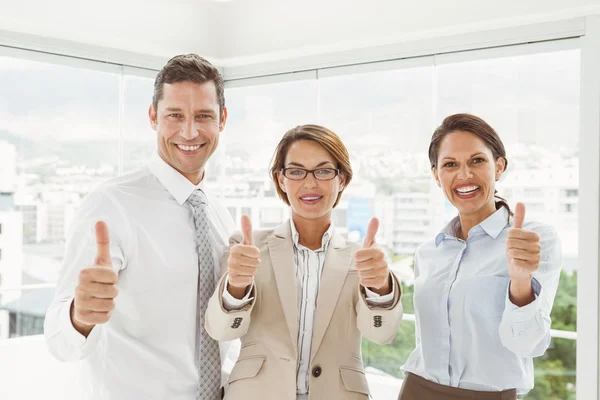 Zuversichtliche glückliche Geschäftsleute, die im Amt mit erhobenem Daumen gestikulieren — Stockfoto