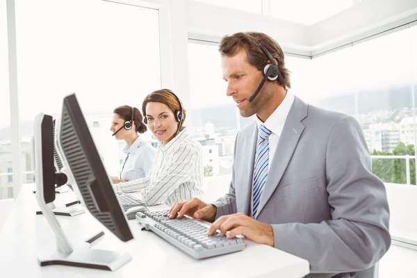 Gente de negocios con auriculares usando computadoras en la oficina —  Fotos de Stock