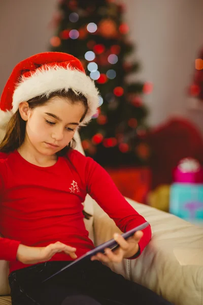 Festive little girl using tablet pc on couch — Stock Photo, Image