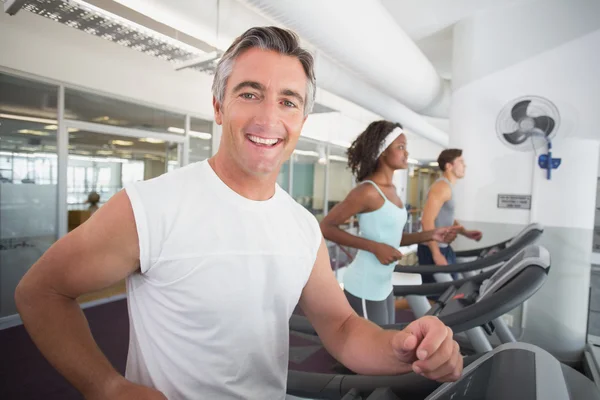 Fit homem correndo na esteira sorrindo para a câmera — Fotografia de Stock