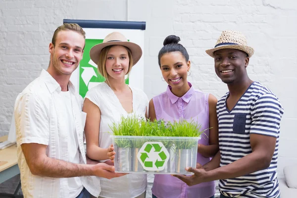 Creative business team holding plant with recycling symbol — Stock Photo, Image
