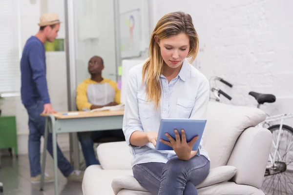 Casual vrouw met behulp van digitale tablet met collega's achter in office — Stockfoto