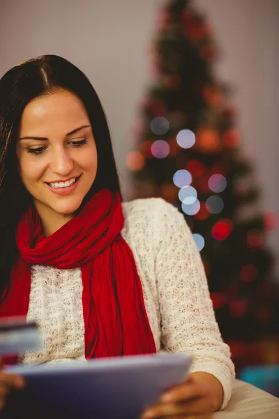 Pretty brunette shopping online with tablet at christmas — Stock Photo, Image
