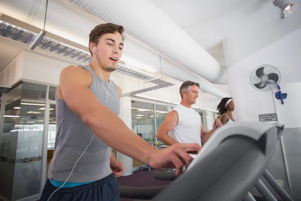 Fit man running on treadmill listening to music — Stock Photo, Image