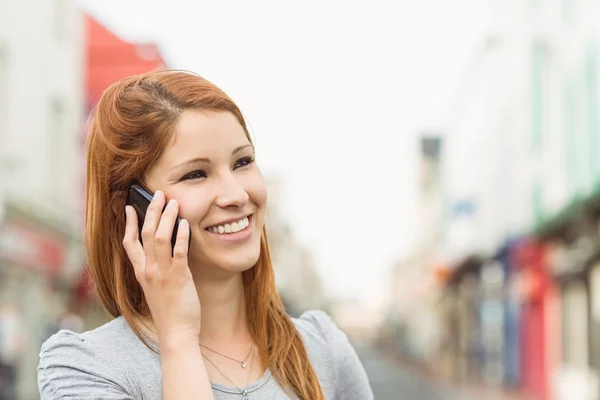 Uśmiechający się wzywając ktoś z jej telefonu komórkowego — Zdjęcie stockowe