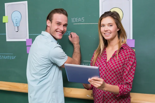 Creative business people with digital tablet by blackboard — Stock Photo, Image