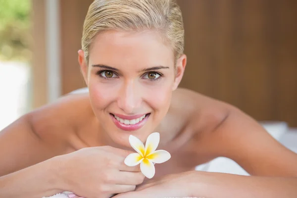 Mulher segurando flor na mesa de massagem — Fotografia de Stock