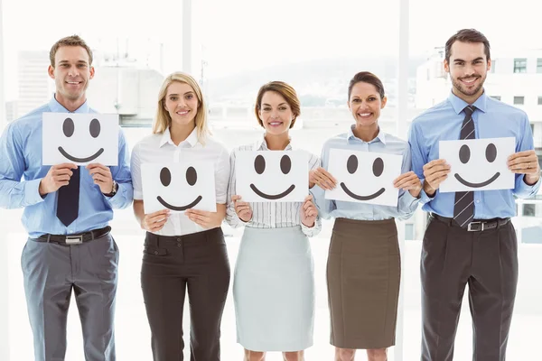 Business people holding happy smileys in office — Stock Photo, Image