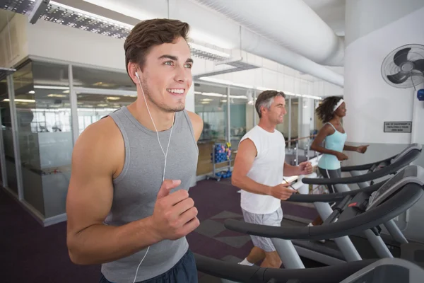 Hombre en forma corriendo en la cinta de correr escuchando música —  Fotos de Stock