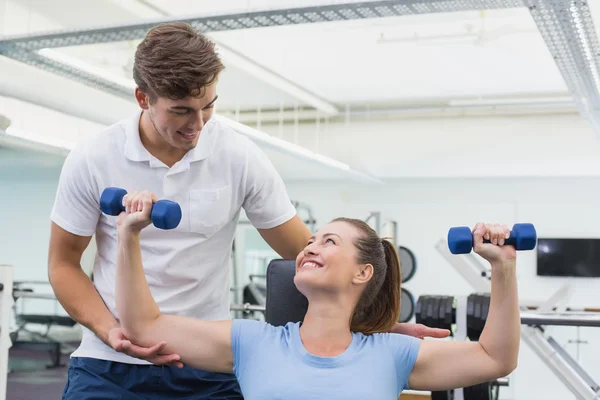 Personal trainer helping client lift dumbbell — Stock Photo, Image