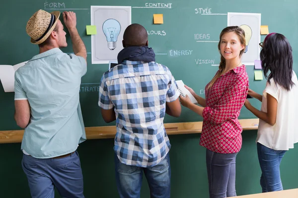 Creative business people at work by blackboard — Stock Photo, Image