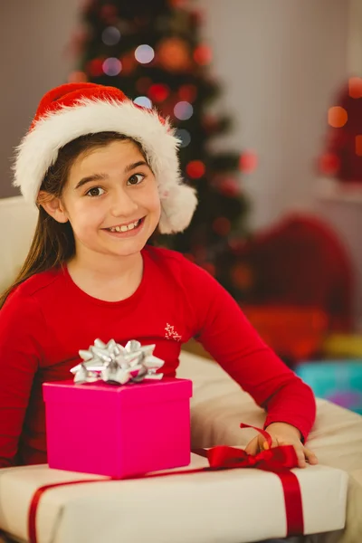 Festliches kleines Mädchen lächelt mit Geschenken in die Kamera — Stockfoto