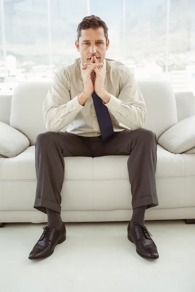 Беспокойный бизнесмен сидит на диване — стоковое фото