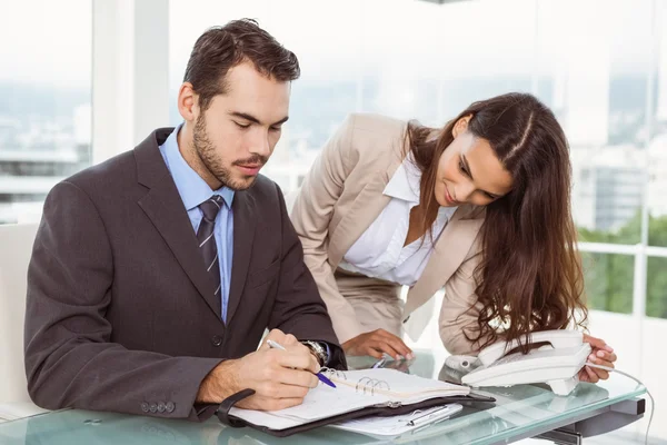 Homme d'affaires et secrétaire regardant journal dans le bureau — Photo