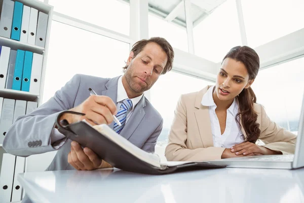 Zakenman en secretaris kijken naar dagboek in office — Stockfoto