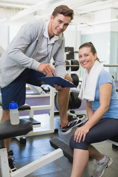Personal trainer and client looking at clipboard together — Stock Photo, Image