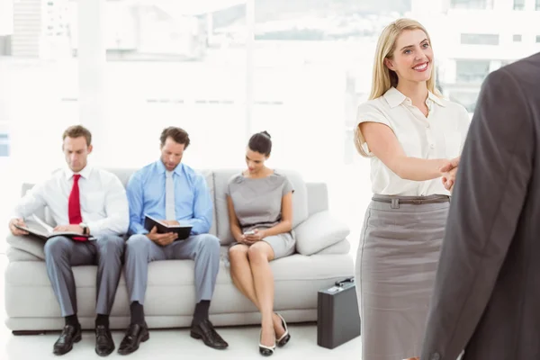 Empresario estrechando la mano con la mujer, además de las personas que esperan la entrevista — Foto de Stock