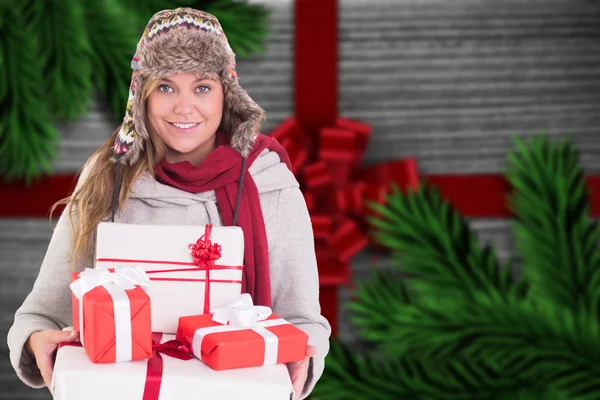 Imagem composta de loira feliz em roupas de inverno segurando presentes — Fotografia de Stock
