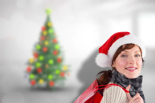 Zusammengesetztes Bild einer lächelnden Frau mit Weihnachtsmütze — Stockfoto