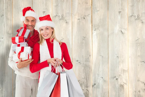 Imagen compuesta de feliz pareja festiva con regalos y bolsas — Foto de Stock