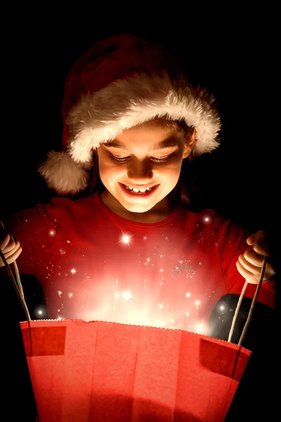 Zusammengesetztes Bild eines kleinen Mädchens beim Öffnen eines magischen Weihnachtsgeschenks — Stockfoto