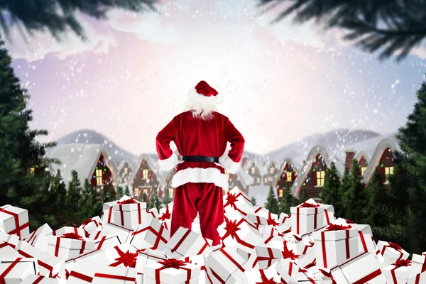 Composite image of santa standing on pile of gifts — Stock Photo, Image