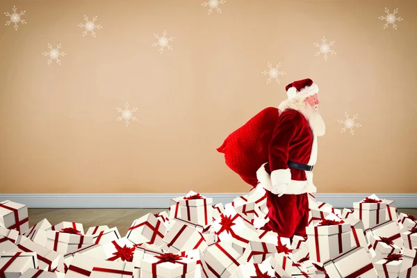 Zusammengesetztes Bild vom Weihnachtsmann, der auf einem Haufen von Geschenken wandelt — Stockfoto