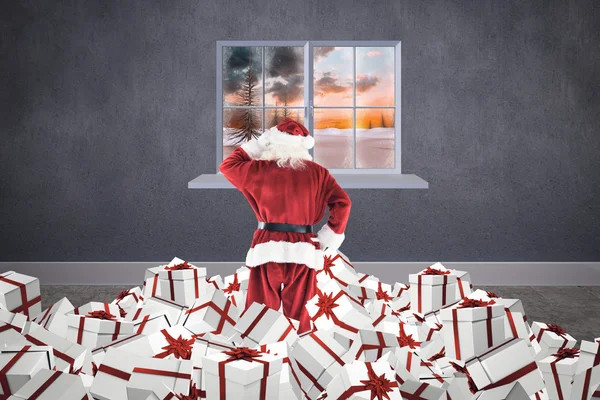 复合图像的圣诞老人站在那堆礼物 — 图库照片