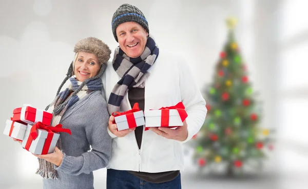 Imagen compuesta de pareja madura festiva sosteniendo regalos de Navidad —  Fotos de Stock