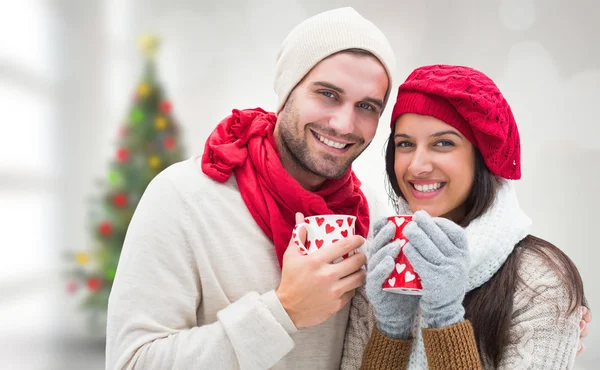 Imagen compuesta de pareja de invierno sosteniendo tazas —  Fotos de Stock