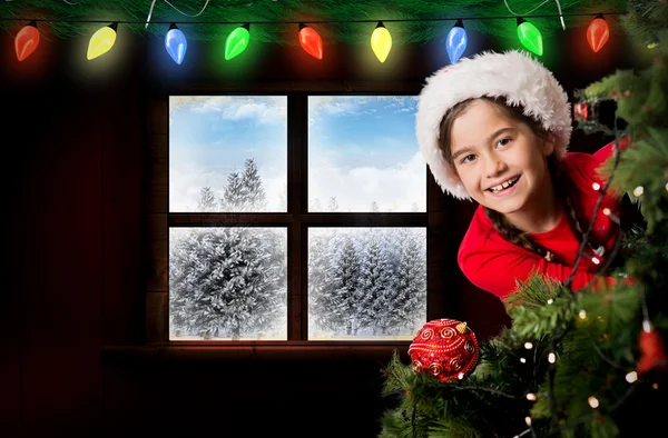 Festmädchen schaut hinter Weihnachtsbaum — Stockfoto