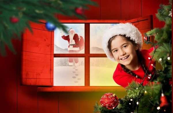 Праздничная девушка смотрит из-за рождественской елки — стоковое фото