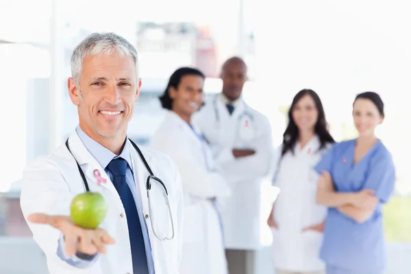 Composite image of mature doctor holding an apple — Stock Photo, Image