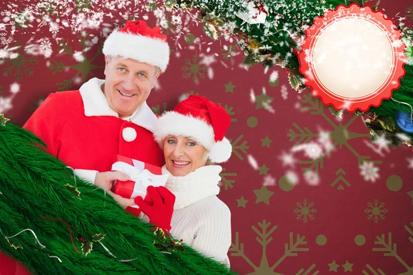 Composite image of festive mature couple holding gift — Stock Photo, Image